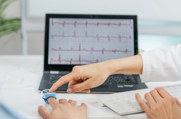 Biofeedback training session. Monitoring heart rate with a sensor attached to client’s  finger. Therapist explaining heartrate patterns