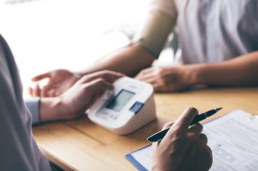 Doctor is using a pulse meter to measure the pressure of the patient at the hospital.