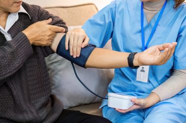 Doctor take care of elderly by helping to check their blood pressure.